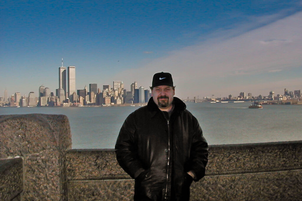 Ein Beispiel für die frühe digitale Fotografie. Auf diesem Farbbild stehe ich auf Liberty Island vor einer Mauer. Im Hintergrund sieht man die Skyline von New York.