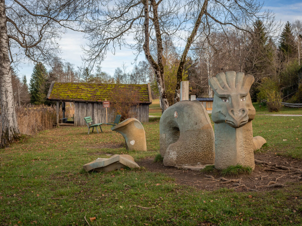 Die Skulptur eines nett aussehenden Seeungeheuers vor der Schuhstation am Seeufer des Bayersoiener See.