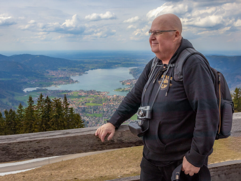 Der Autor dieses Artikels ist auf diesem Bild mit einer umgehängten Kamera vom Typ Minolta Hi-Matic 7 sII auf dem Wallberg zu sehen. Im Hintergrund sieht man bis ins Tal auf den Tegernsee.